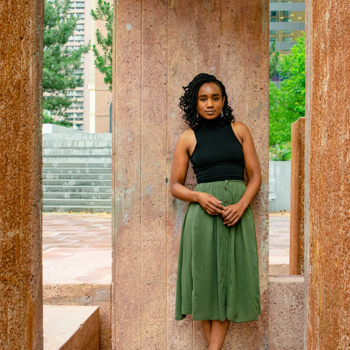 Jasmine Wiley wears black top and green skirt, stands between pillars